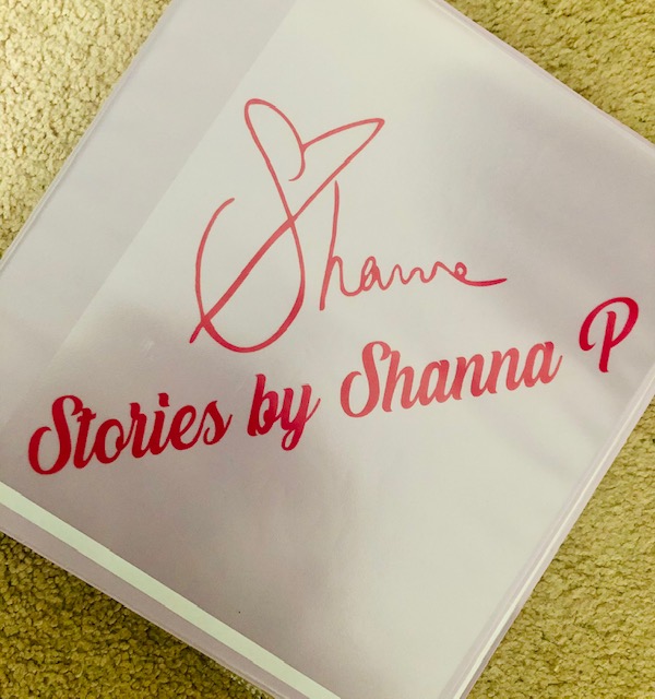 A pink binder with the words "Stories by Shanna P" in red, with Shanna Pikora's signature. 